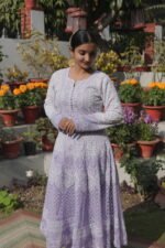 Woman in purple dress among flowers.